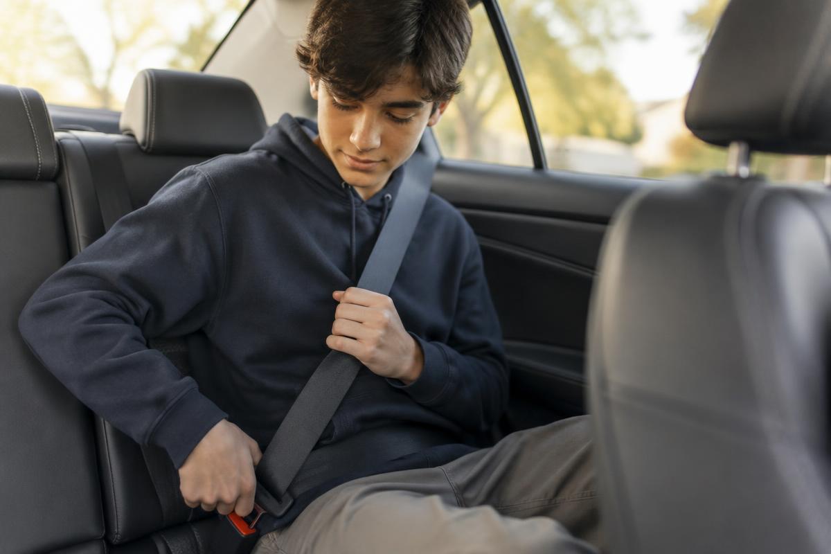 Teenager buckling a seat belt in the back seat of a car
